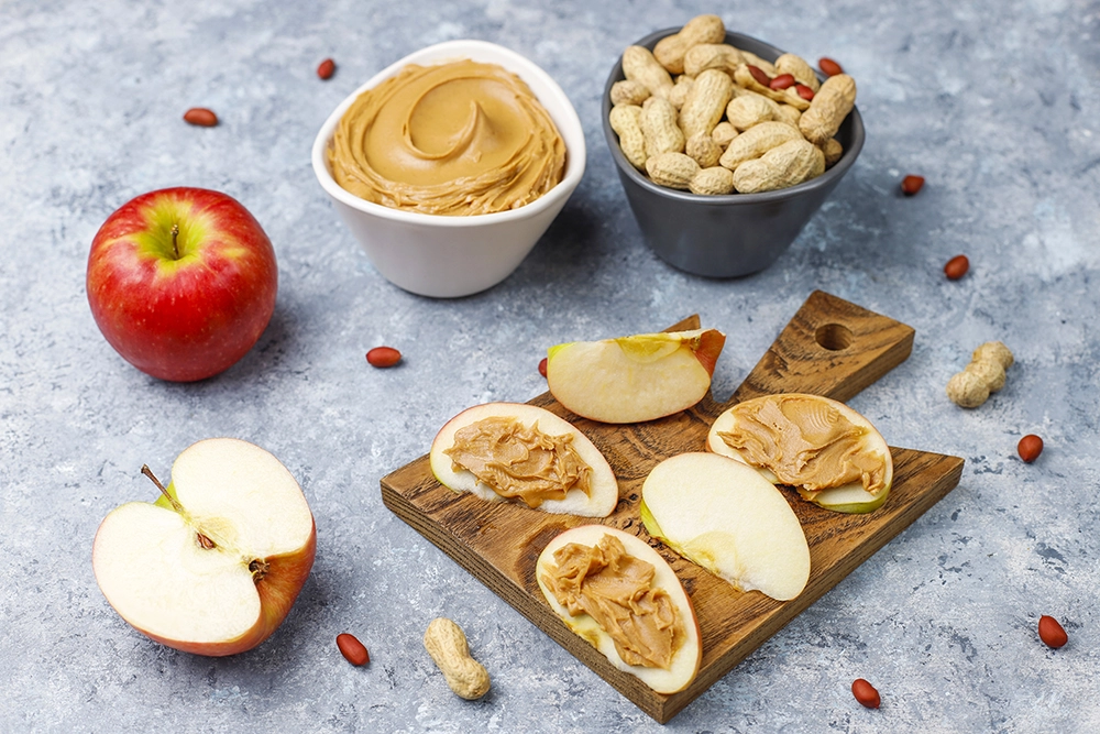 a peanut butter and apple slices on a cutting board