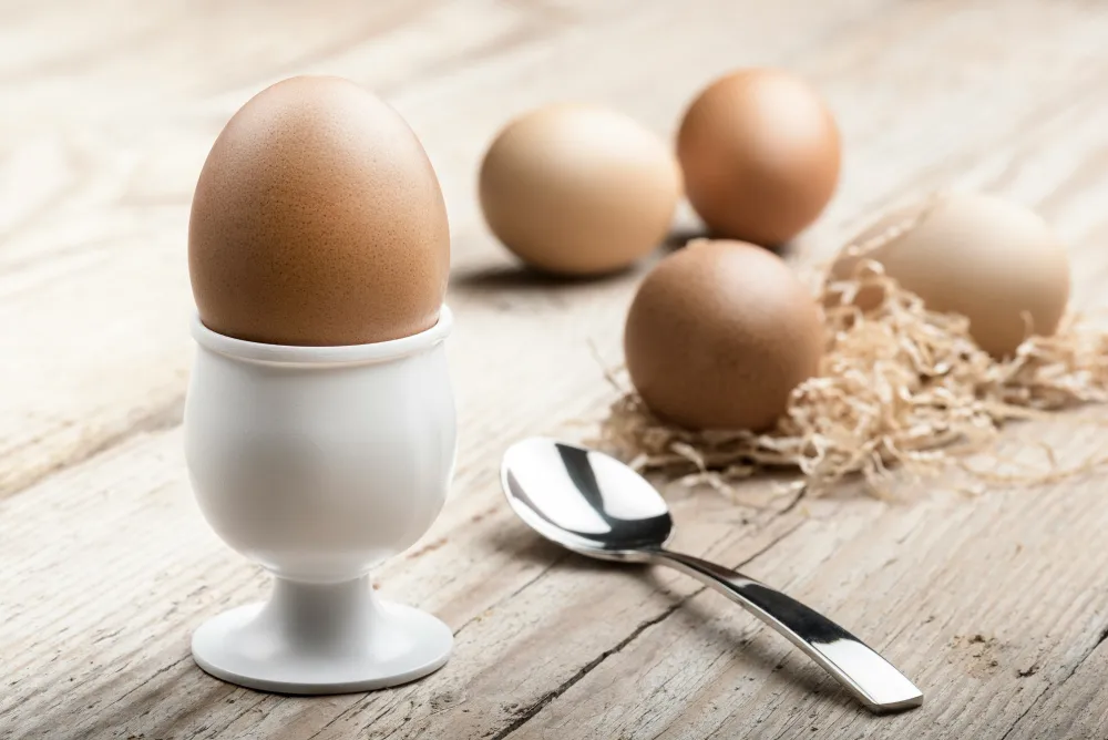 a boiled egg in a cup next to several eggs