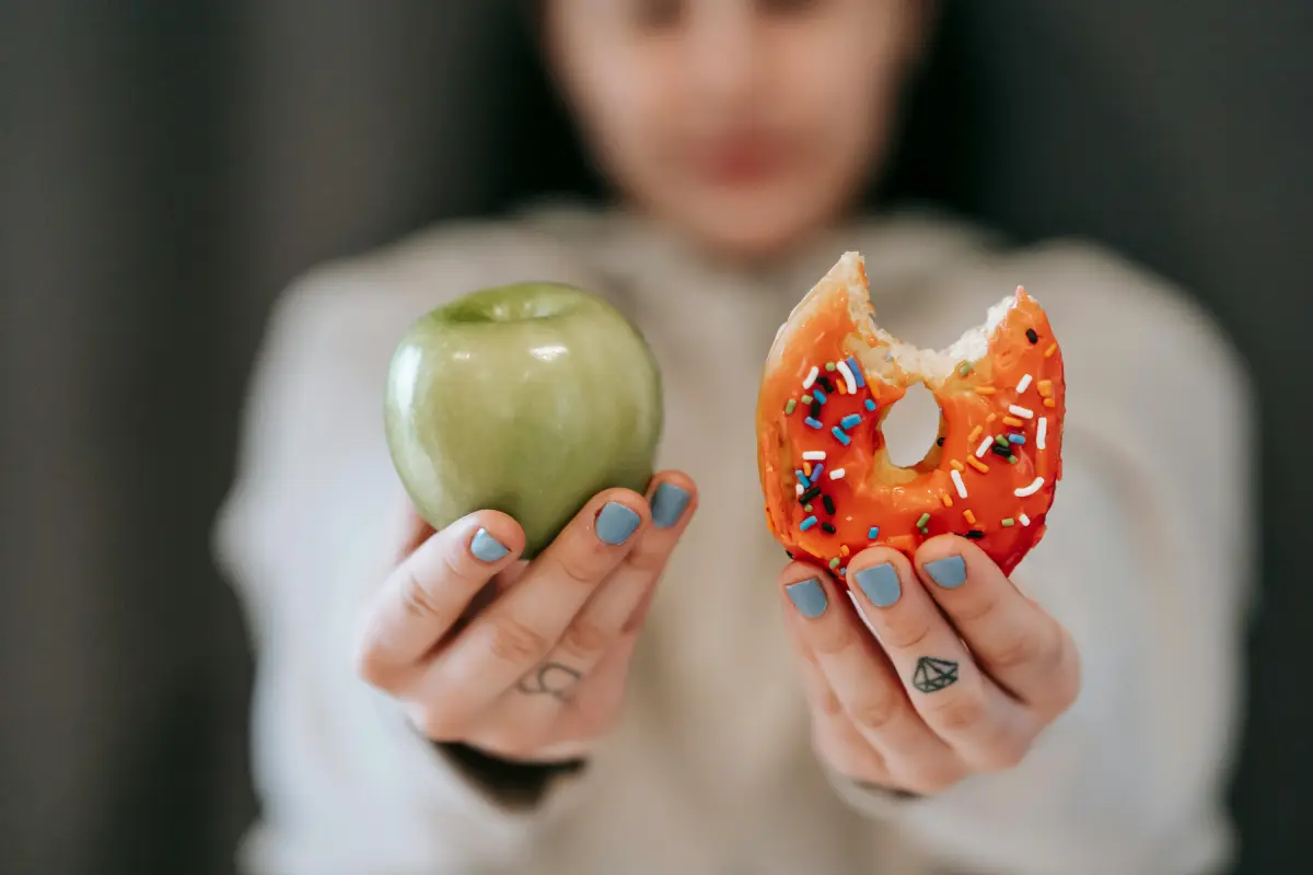 a woman holding an apple and a donut